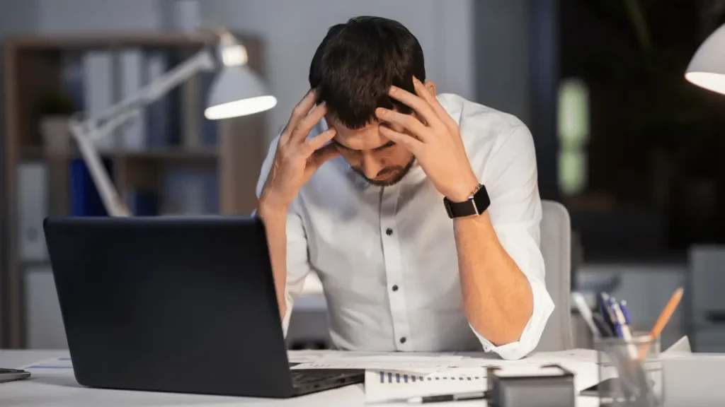 riscos psicossociais no trabalho esg 3 Homem cansado com as mãos no rosto.